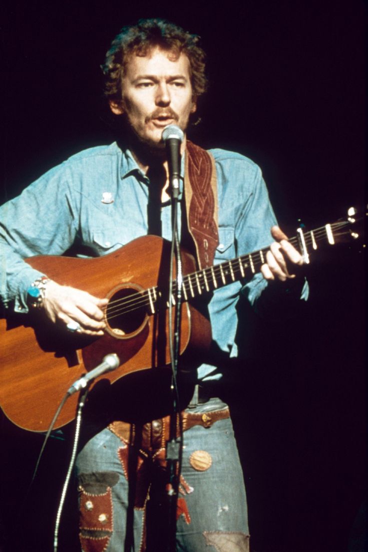 a man holding a guitar while standing in front of a microphone