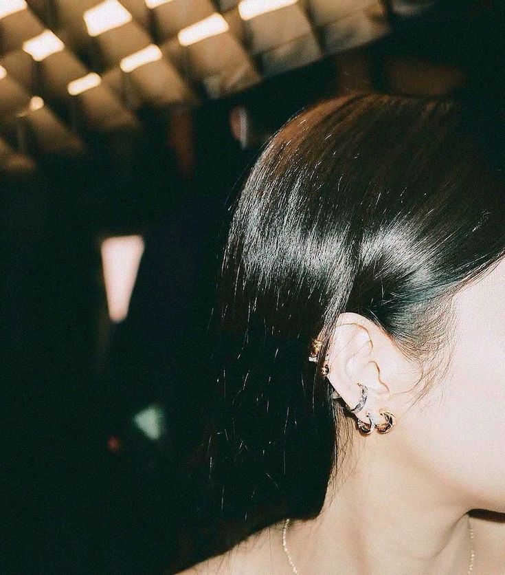 a close up of a person with ear rings on their ears and hair in the background