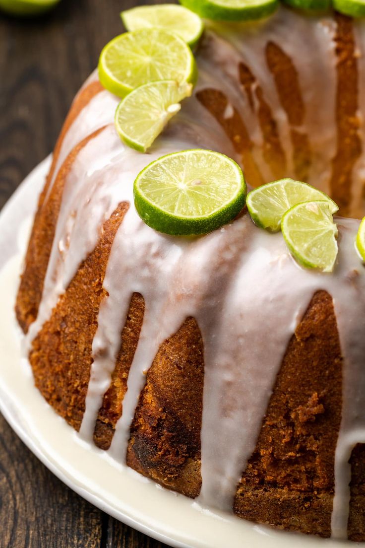 a bundt cake with limes and sliced limes on top, sitting on a white plate