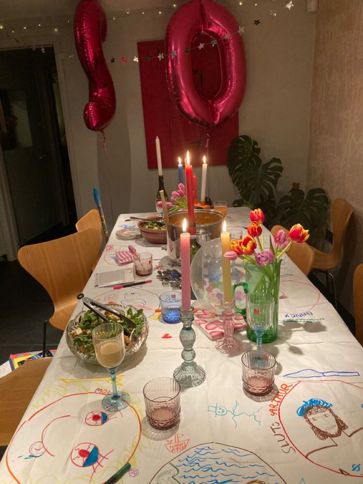 the table is set for a birthday party with candles and flowers in vases on it