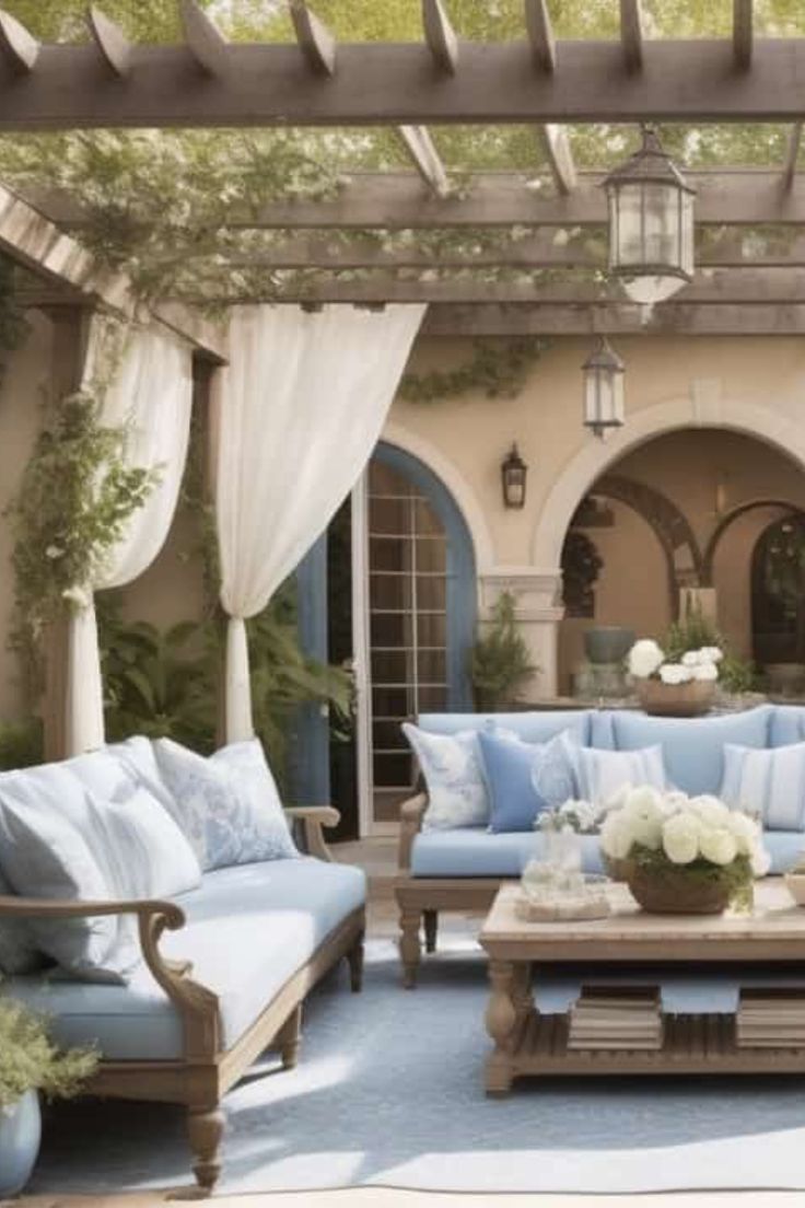 an outdoor living room with blue couches and white flowers in vases on the coffee table