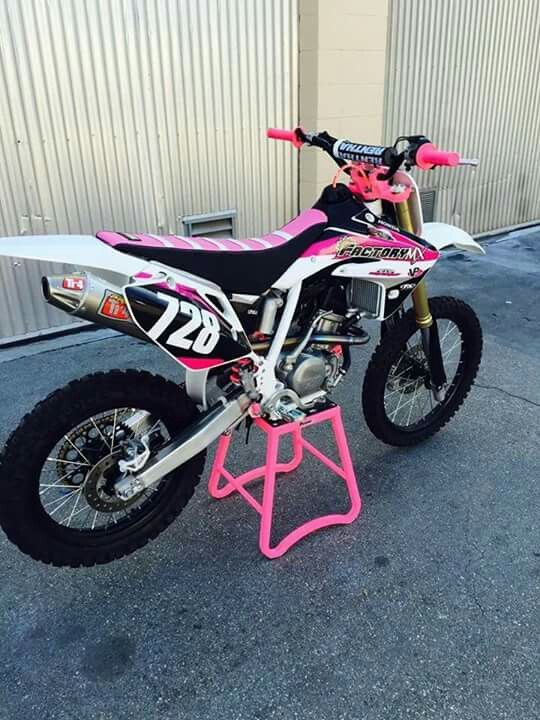 a pink dirt bike parked in front of a building