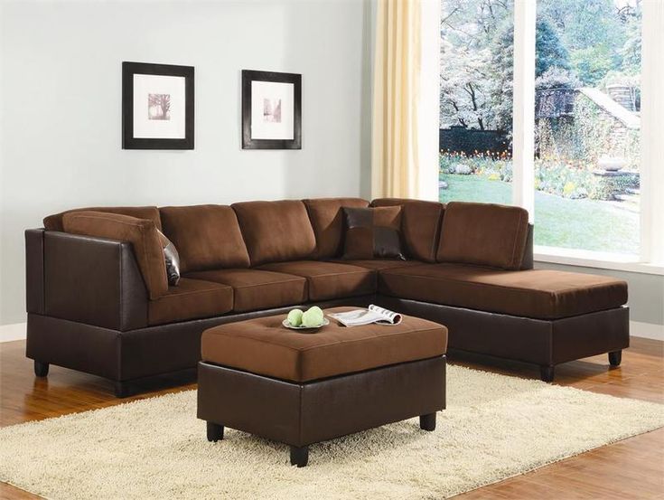 a living room with a brown sectional couch and footstool in front of a window