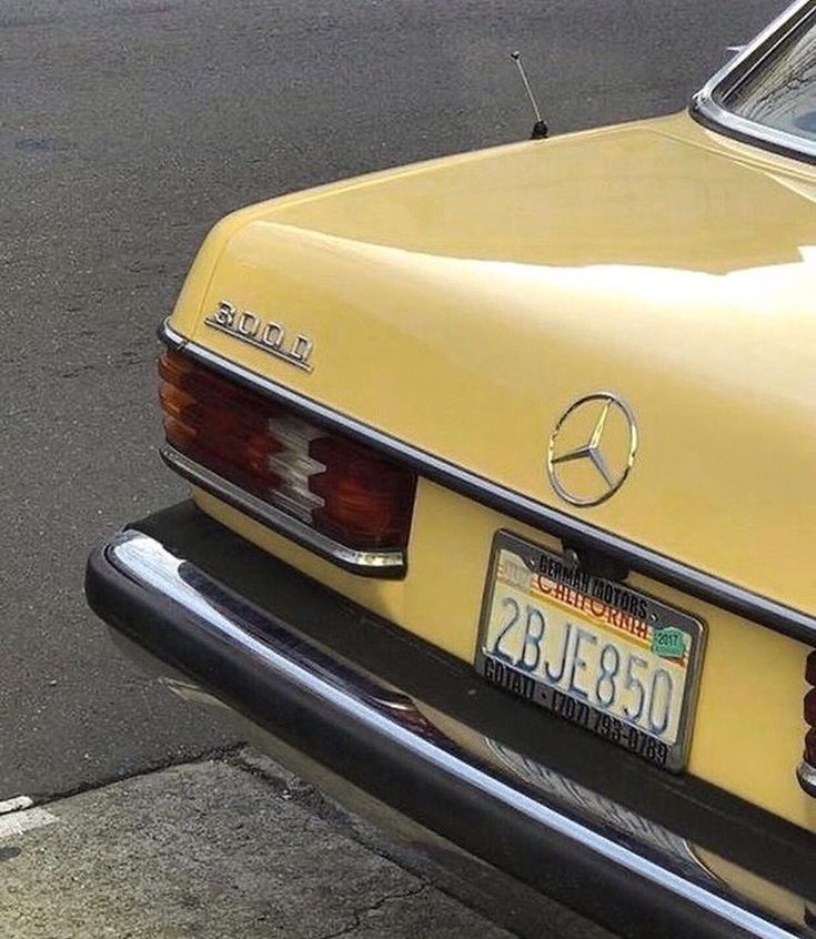 an old yellow mercedes benz is parked on the side of the road with its license plate