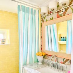 a bathroom with a sink, mirror and shower curtain