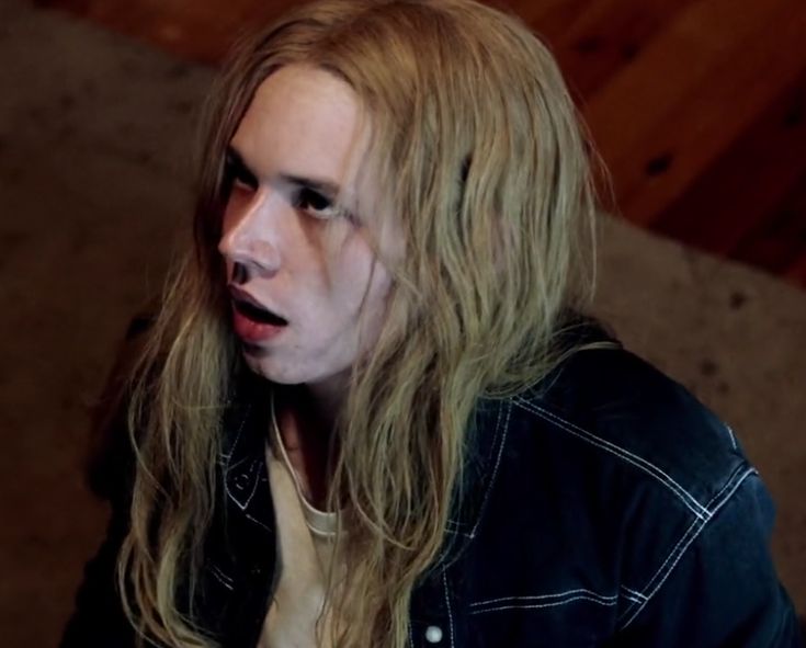 a man with long blonde hair wearing a black jacket