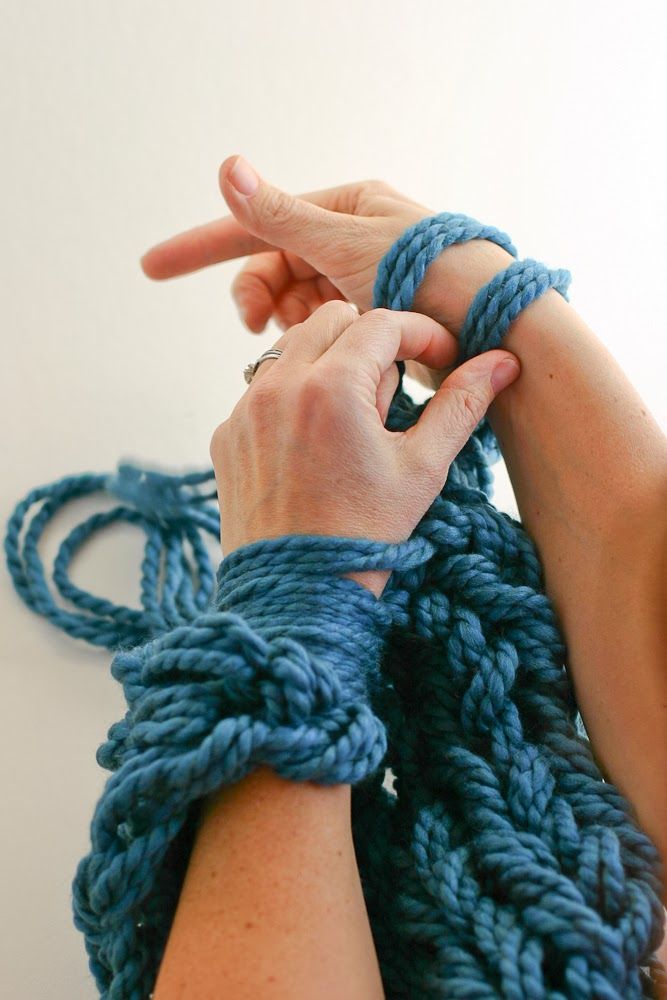 the woman is knitting her blue hand knitted armwars with two hands together