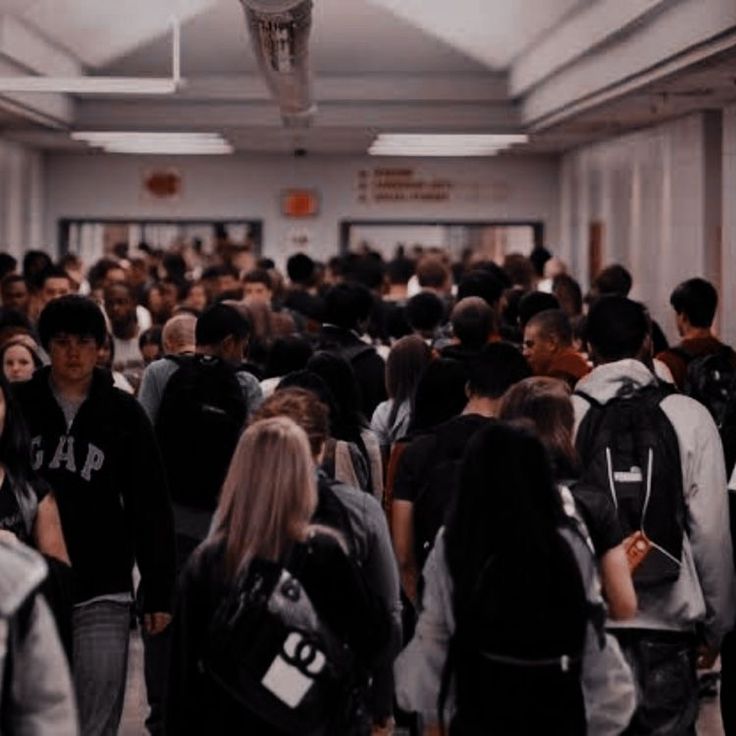 a large group of people are walking down the hallway in an office building with backpacks on their backs