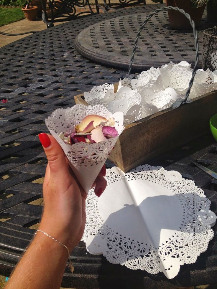 a person holding up a paper cone with some food in it on top of a table