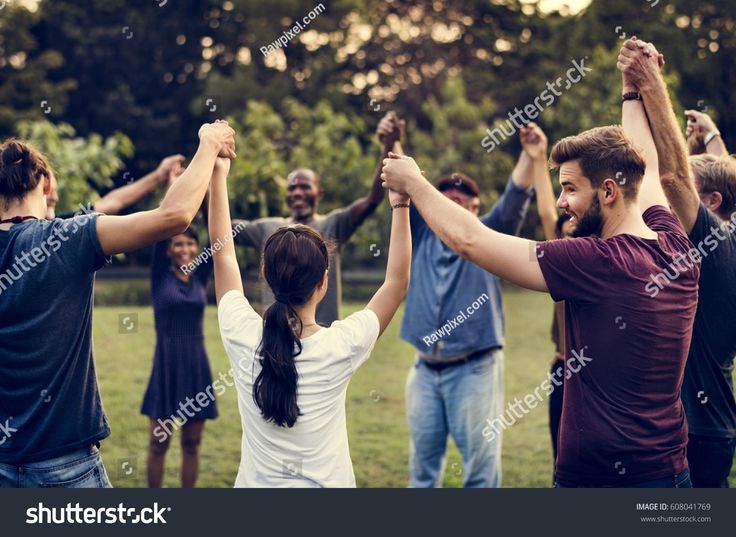 group of people holding hands in the air with their arms raised and looking at each other