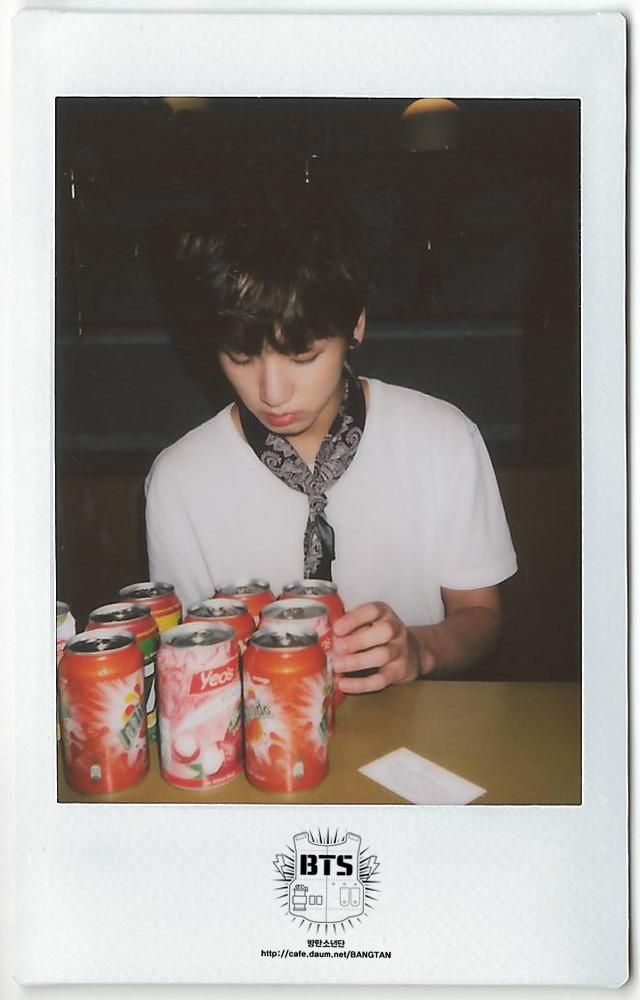 a young man sitting at a table with six cans