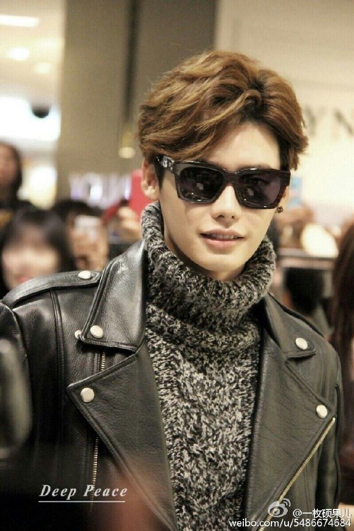 a young man wearing sunglasses and a black leather jacket is standing in front of a crowd