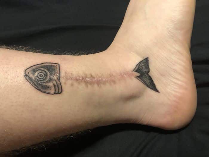 a person with a tattoo on their foot has an eye and arrow in the middle