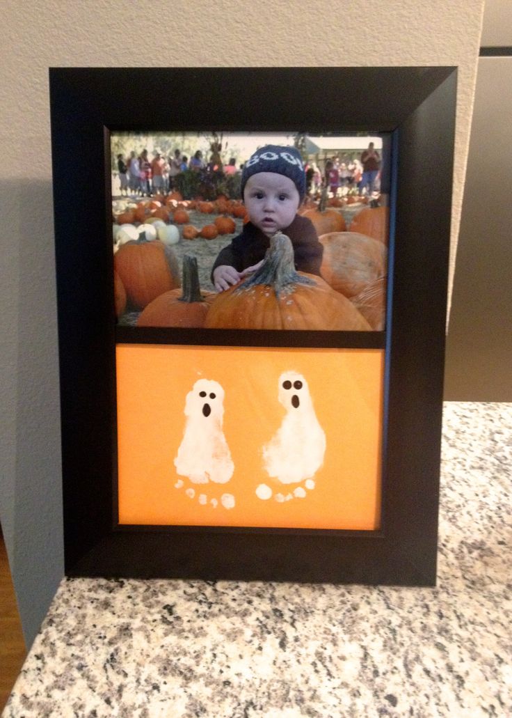 an image of a baby in a frame with two ghost on the ground next to pumpkins