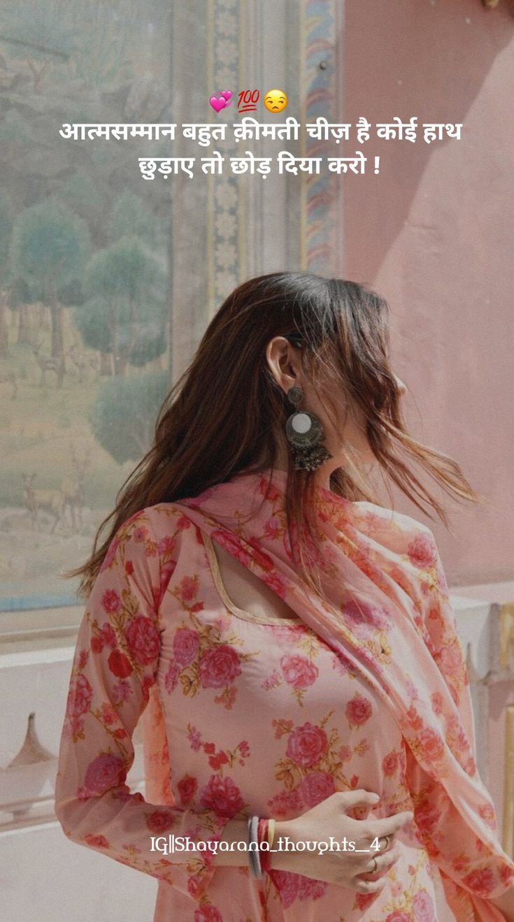 a woman with long hair wearing a pink floral print sari and earrings, standing in front of a painting