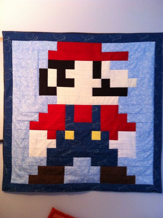 an old school video game character quilt hanging on the wall above a bed in a bedroom