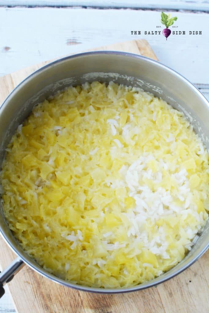 a pan filled with rice sitting on top of a wooden cutting board