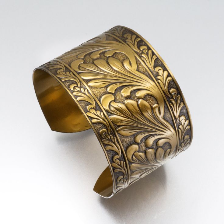 an intricately designed brass cuff bracelet on a white background