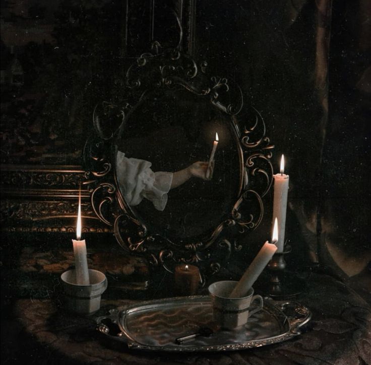 candles are lit in front of a mirror with an image of a doll on it