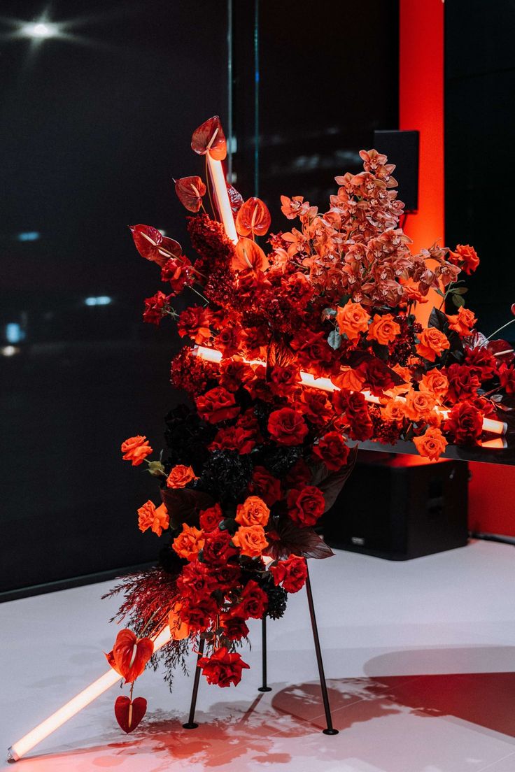 an arrangement of red flowers is displayed on a stand