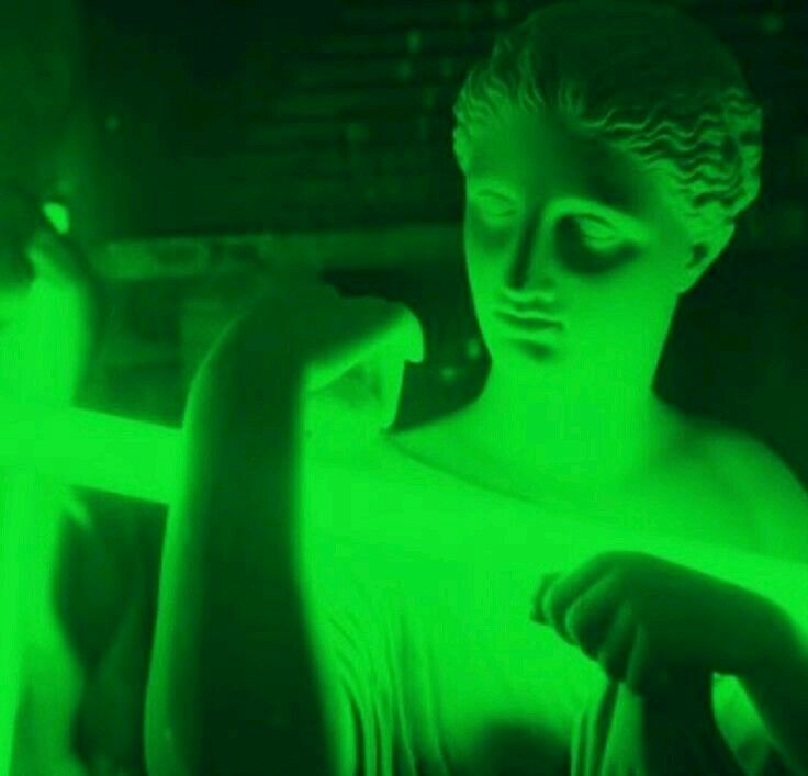 a statue is shown in green light with the woman's face glowing behind it