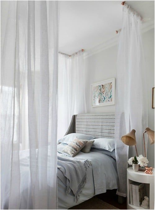 a white bedroom with sheer curtains and a bed