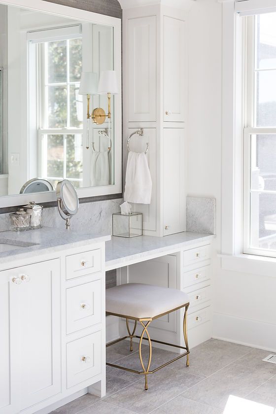 a white bathroom with marble counter tops and large mirrors on the wall, along with two stools