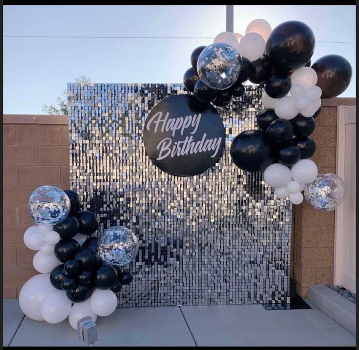 black and white balloon arch with happy birthday sign