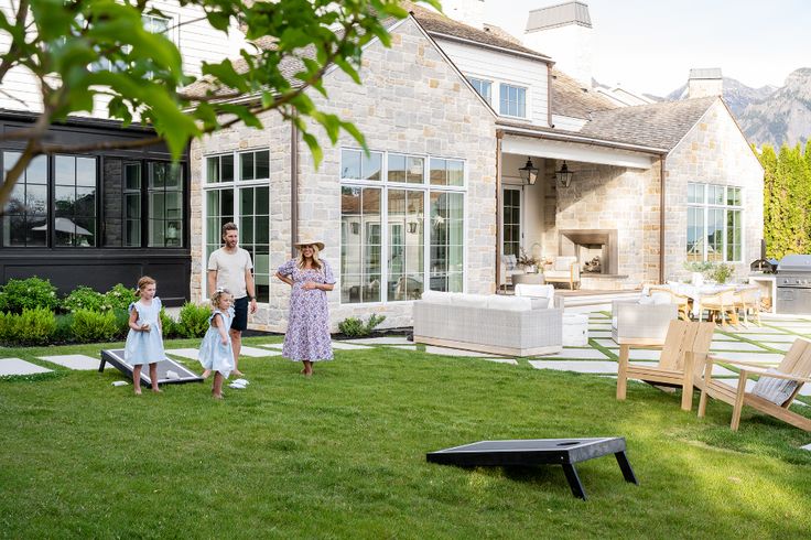 two children and an adult playing in the yard with lawn furniture, chairs and tables