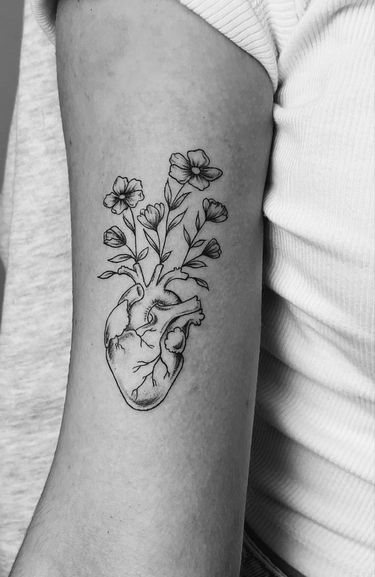 a black and white photo of a heart with flowers on the inside of its arm