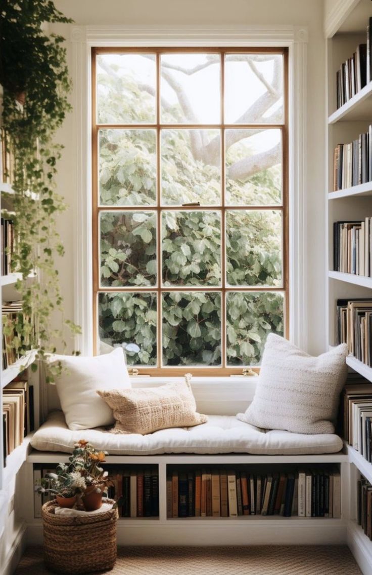 a window seat in front of a bookshelf filled with lots of books and plants