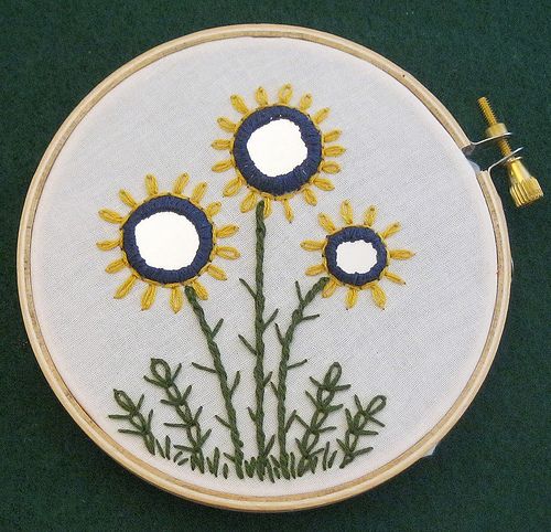 a close up of a embroidery on a green surface with two small holes in the center