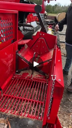 a man standing next to a red tractor with metal grates on it's side