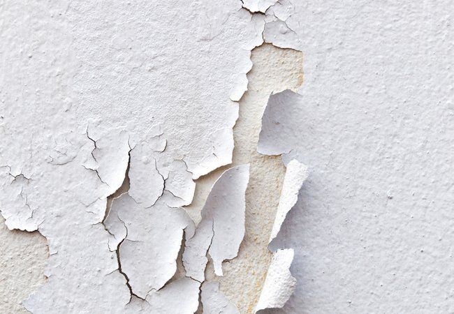 peeling paint on a white wall with chipping off the top and bottom part missing