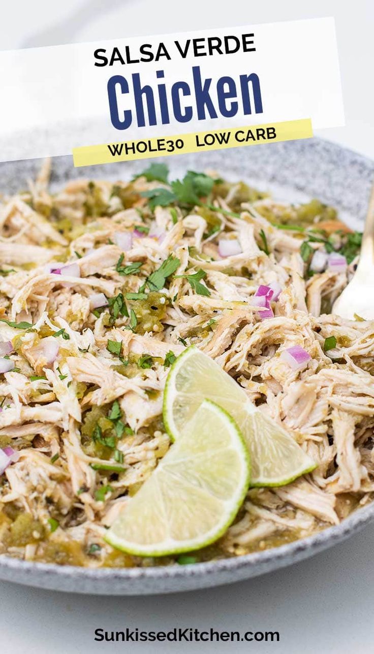 a bowl filled with shredded chicken and garnished with cilantro, lime wedges