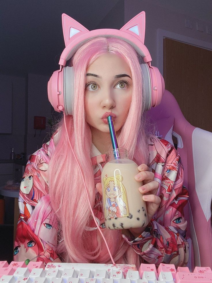 a girl with pink hair wearing headphones and holding a drink