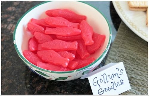 a bowl full of red gummy bears next to a plate with cookies on it