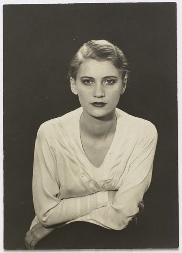 an old black and white photo of a woman with her arms folded over her chest