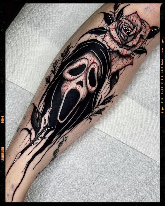 a black and white tattoo with a rose on the arm, skull and crossbones