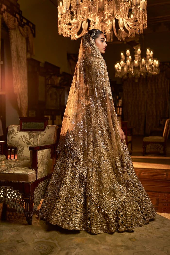 This lehenga set features heavy antique gold embroidery interspersed with bold cut work. The lehenga is further lined with antique gold crush tissue. The blouse shows exaggerated pearl tassels at the sleeve hem, elbow and at the back of the blouse. it is paired with a matching heavy embroidered with tassels on all four sidesFrom Seema Gujral's Falaknuma collection. DELIVERY TIMEPlease allow 8-12 weeks for your outfit to arrive. FABRIC DETAILSNet Professional cleaning only. Traditional Gold Gown With Dupatta, Designer Wear Gown With Gold Embroidery And Traditional Drape, Gold Chandbali Gown For Diwali, Gold Gown With Gold Embroidery And Traditional Drape, Gold Designer Wear Floor-length Dupatta, Gold Anarkali Set With Sheer Dupatta For Reception, Anarkali Style Gold Lehenga With Intricate Embroidery, Unstitched Gold Dupatta For Reception, Gold Traditional Wear With Dupatta For Reception