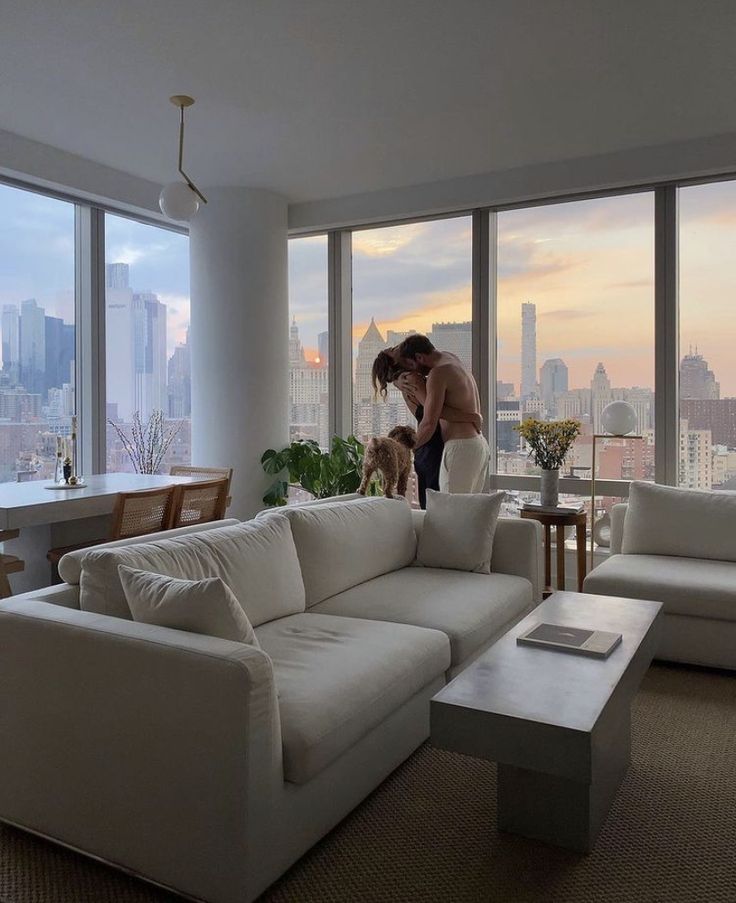 a woman standing on top of a white couch next to a living room filled with furniture