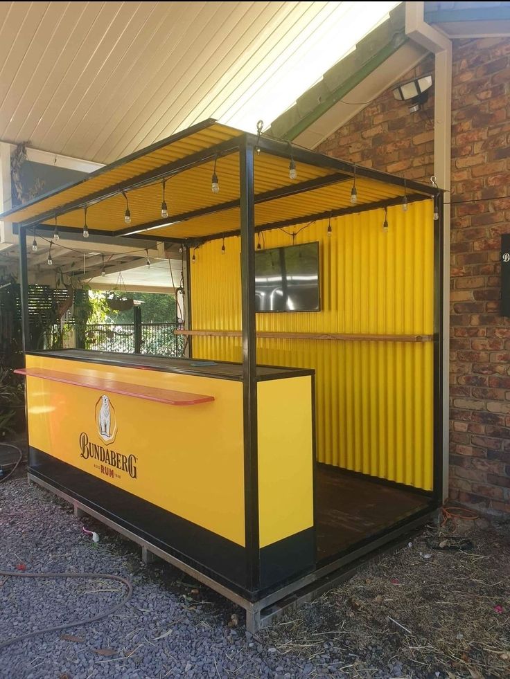 a yellow and black food cart sitting in front of a brick building