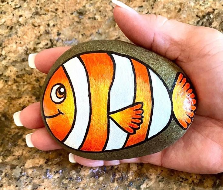 a hand painted rock with an orange and white fish on it