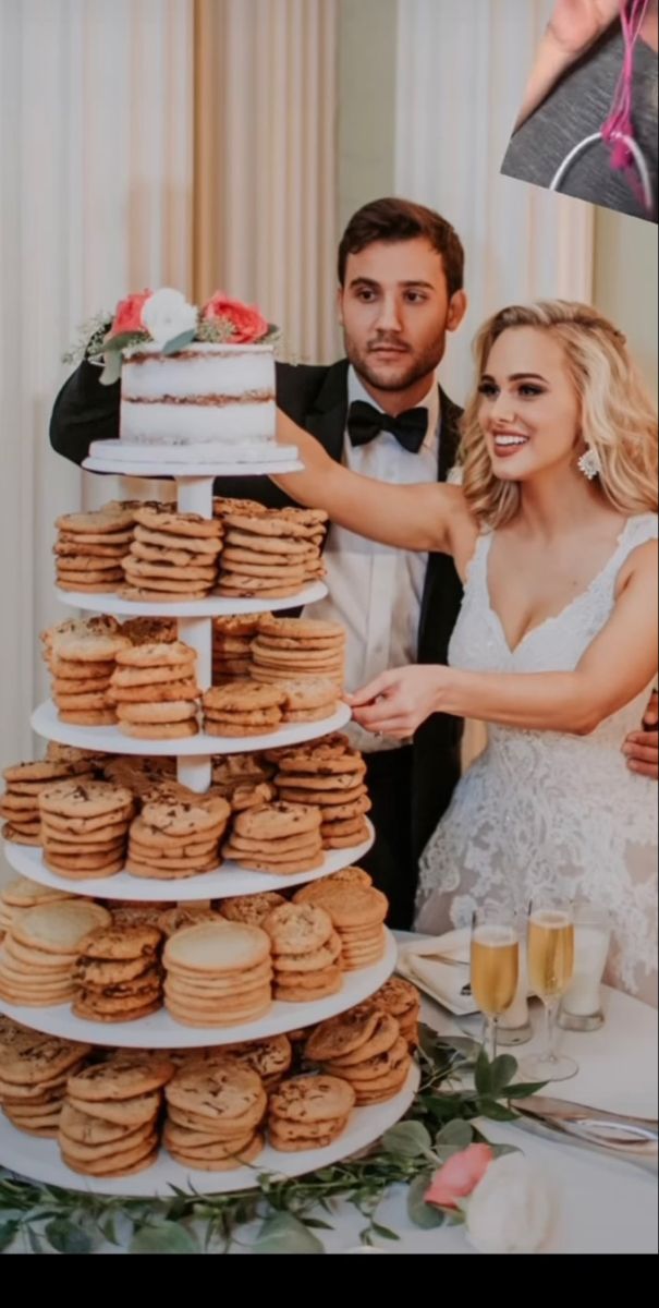 a bride and groom standing next to a large stack of cookies