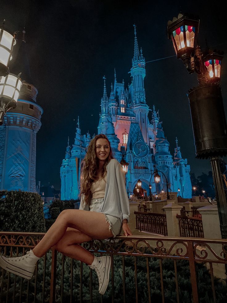 a woman sitting on top of a metal fence next to a light pole and castle