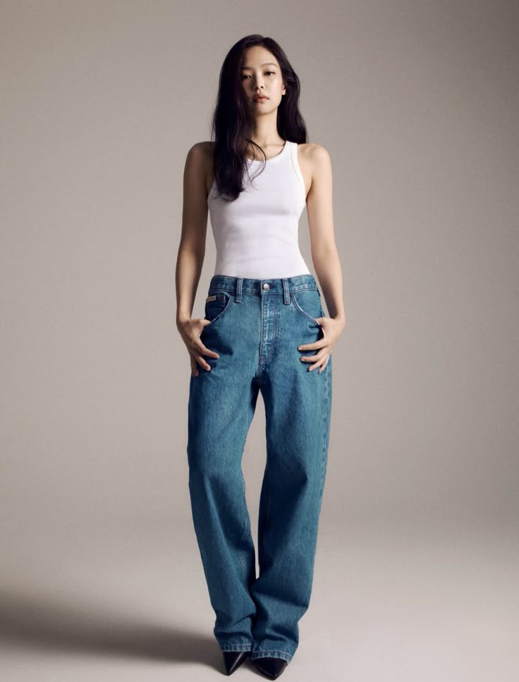 a woman in white shirt and jeans posing for the camera with her hands on her hips