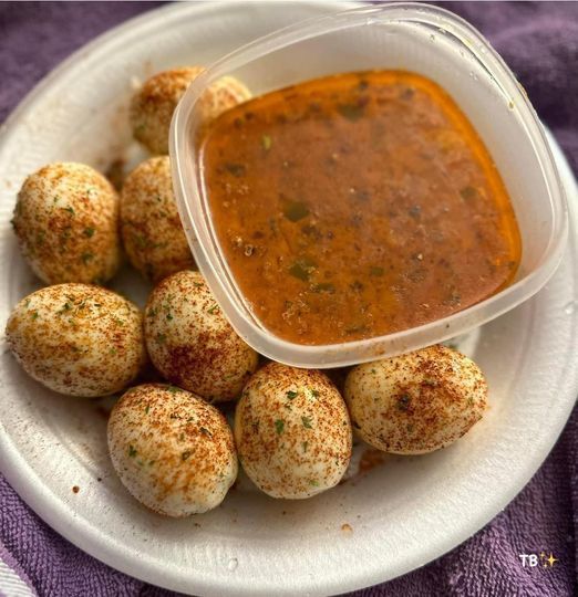 a white plate topped with small balls of food next to a container of dipping sauce