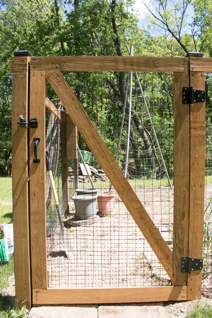 a wooden gate with metal latches on the sides and an animal enclosure behind it