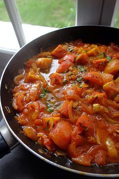 a pan filled with lots of food on top of a stove next to a window