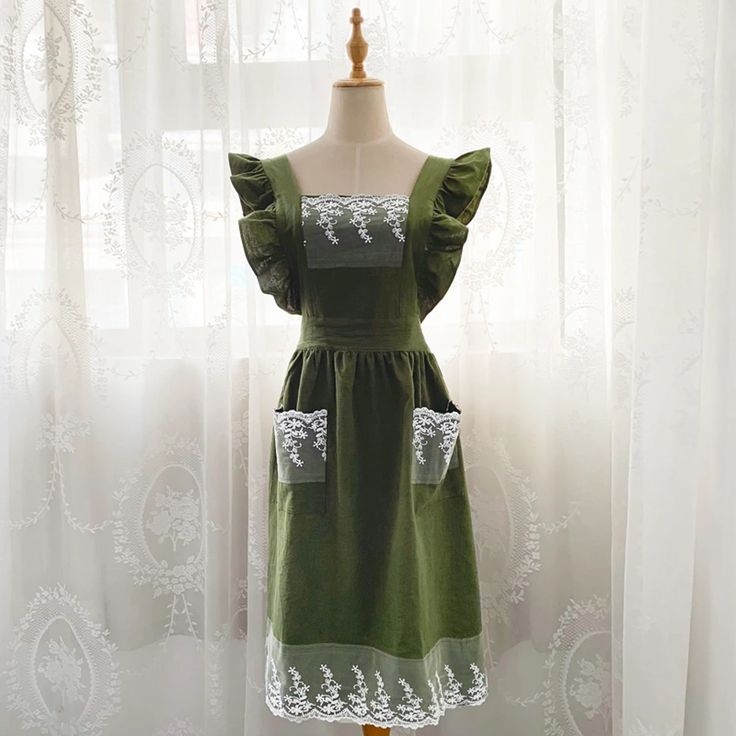 a green dress on a mannequin in front of a window with white curtains